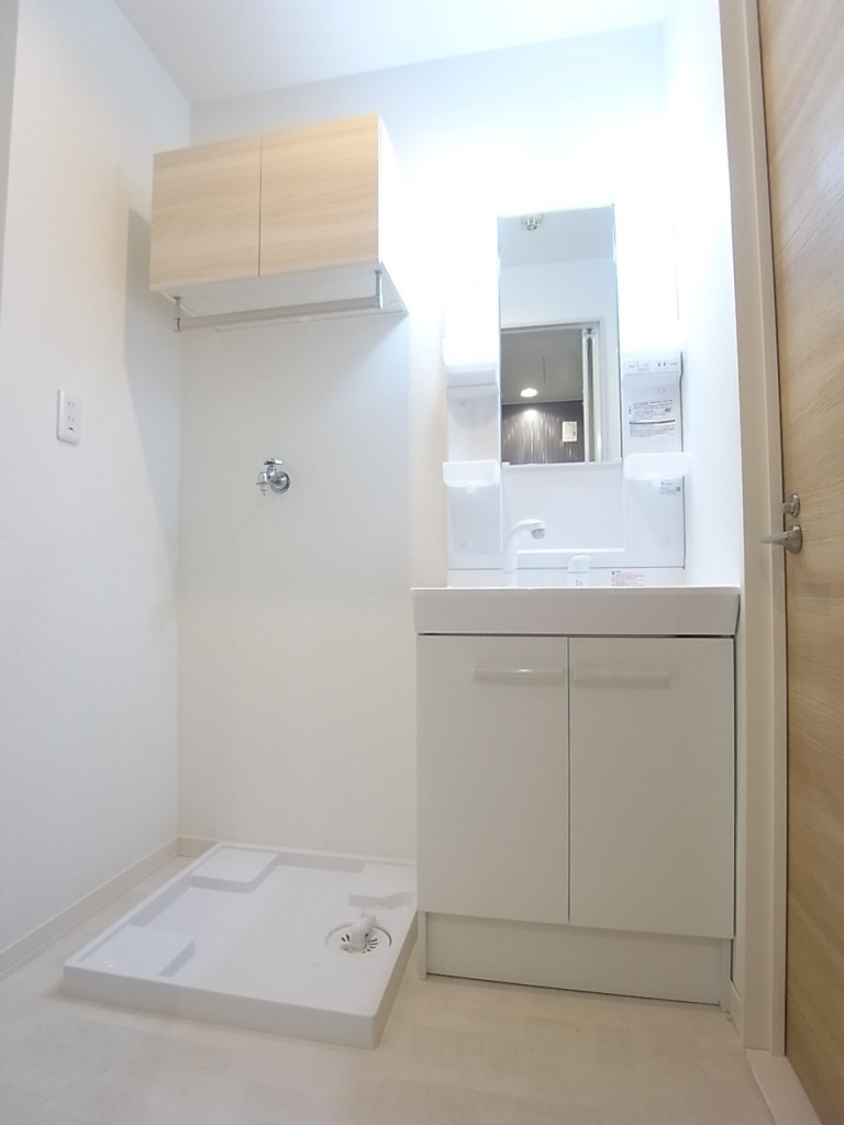 洗面所には洗濯機置き場。上部の棚も便利にお使いいただけます