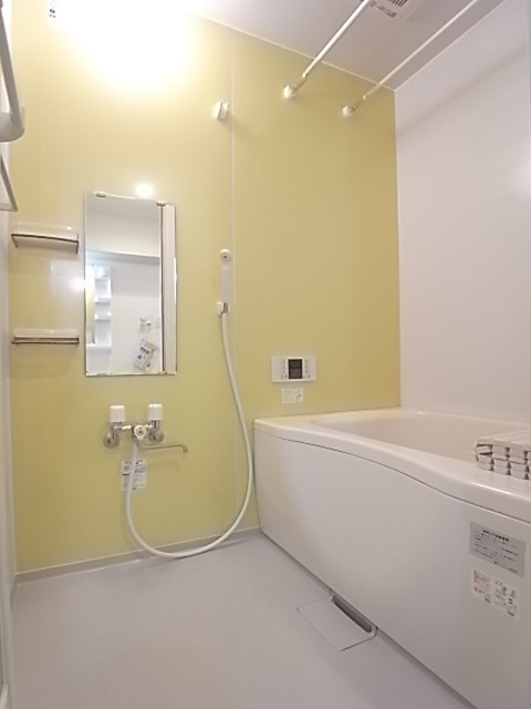 追い焚き、浴室乾燥機付きの浴室。片面は淡い黄色のパネルで明るく感じる。
